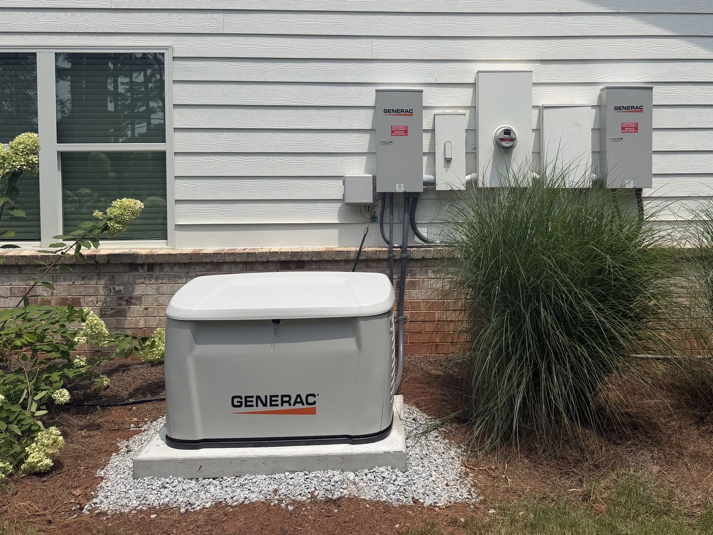 Generac standby generator installed on a concrete pad beside a home, with transfer switches mounted at the meter